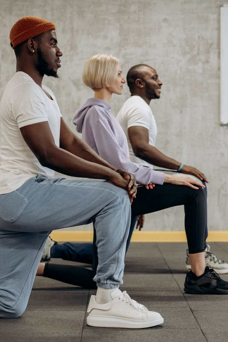 A diverse group of adults practicing lunges in a gym, emphasizing teamwork and fitness.